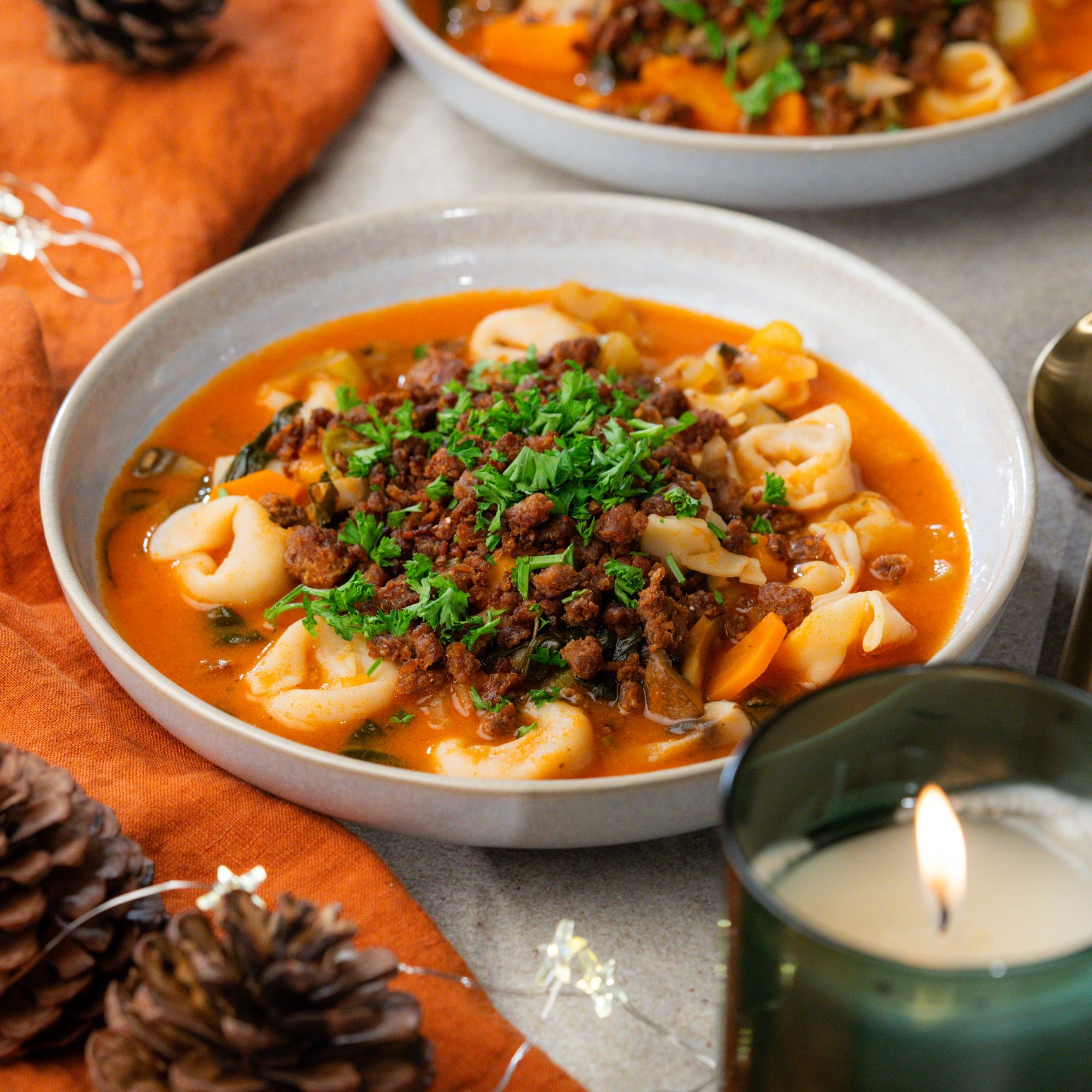 Teller gefüllt mit Tortellini Suppe getoppt mit veganem Hack und Petersilie