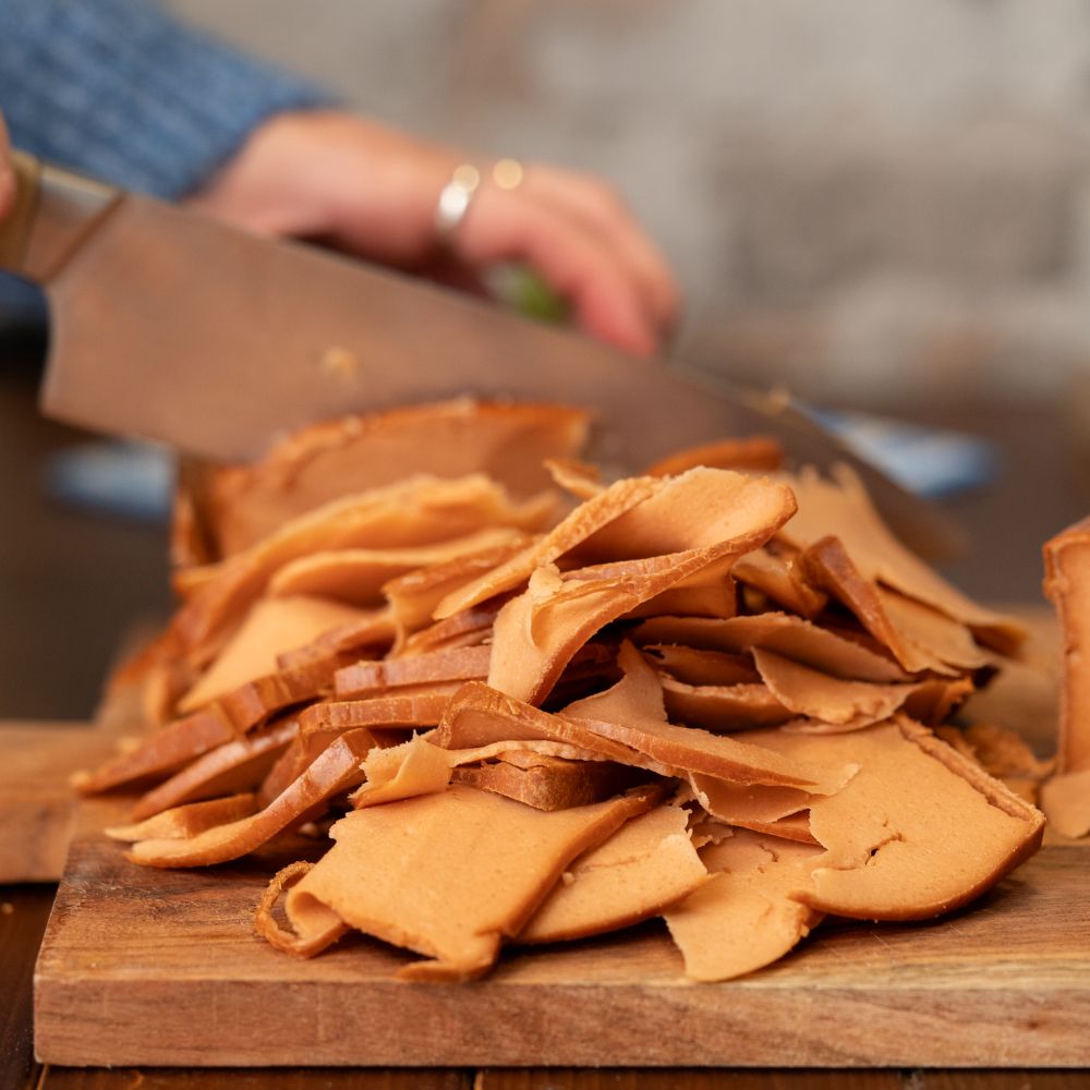 Veganer Leberkäse wird von Person zu dünnen Streifen geschnitten