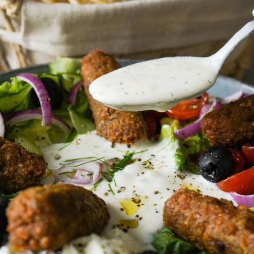 Cevapcici Bowl mit Zaziki auf einem Löffel