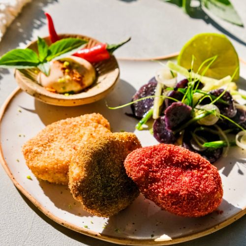 Knusprige vegane Nuggets mit bunten Panaden und violettem Gurkensalat