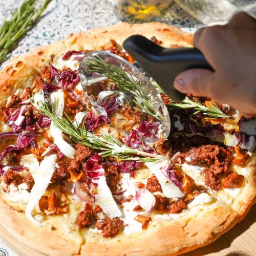 Schneiden der veganen Pizza mit Pfifferlingen und Hack